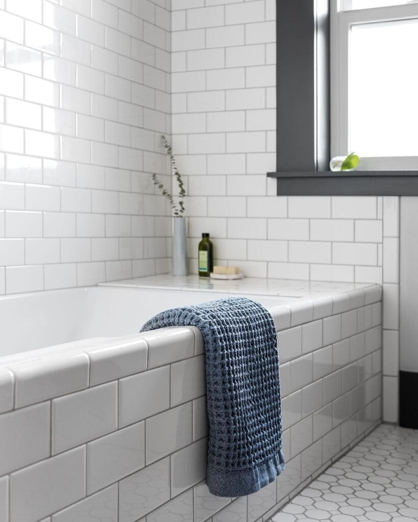 A_Bathroom_With_a_White_Tiled_Tub_and_Wi_